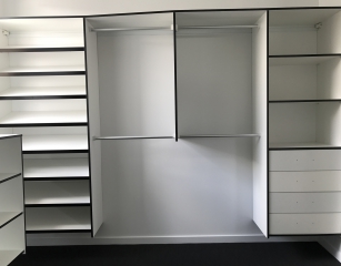 Sloping shoe shelves with half hang and bank of shelves with drawers. All white with Black edge